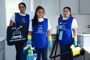 Staff from US Maid posing in a kitchen with their cleaning supplies