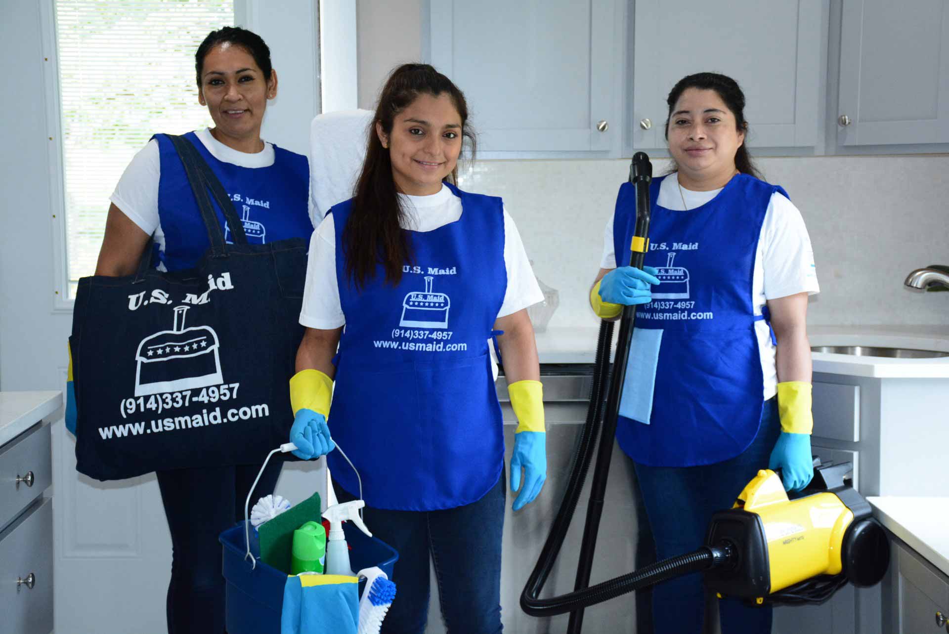 Staff from US Maid posing in a kitchen with their cleaning supplies