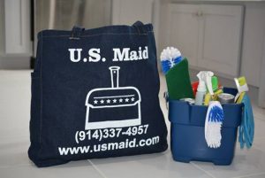 Bag with the US Maid logo on the floor with a bucket of cleaning supplies